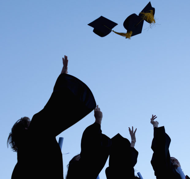 Students throw their mortarboards in the air