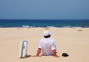 man on beach with suitcase