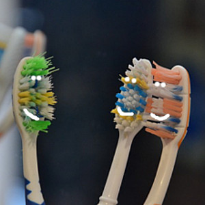 three toothbrushes with smiley faces drawn on